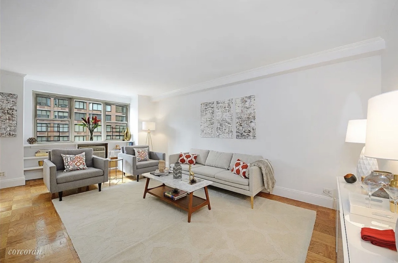 The second living configuration — open-flow sitting room with two armchairs and a sofa, city-view windows, the apartment's secondary entertaining program