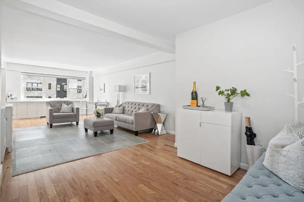 345 East 56th Street #8E — the open-plan living-and-dining-and-kitchen flow with beamed-ceiling detail, hardwood flooring, and the renovated finish register through the principal living space