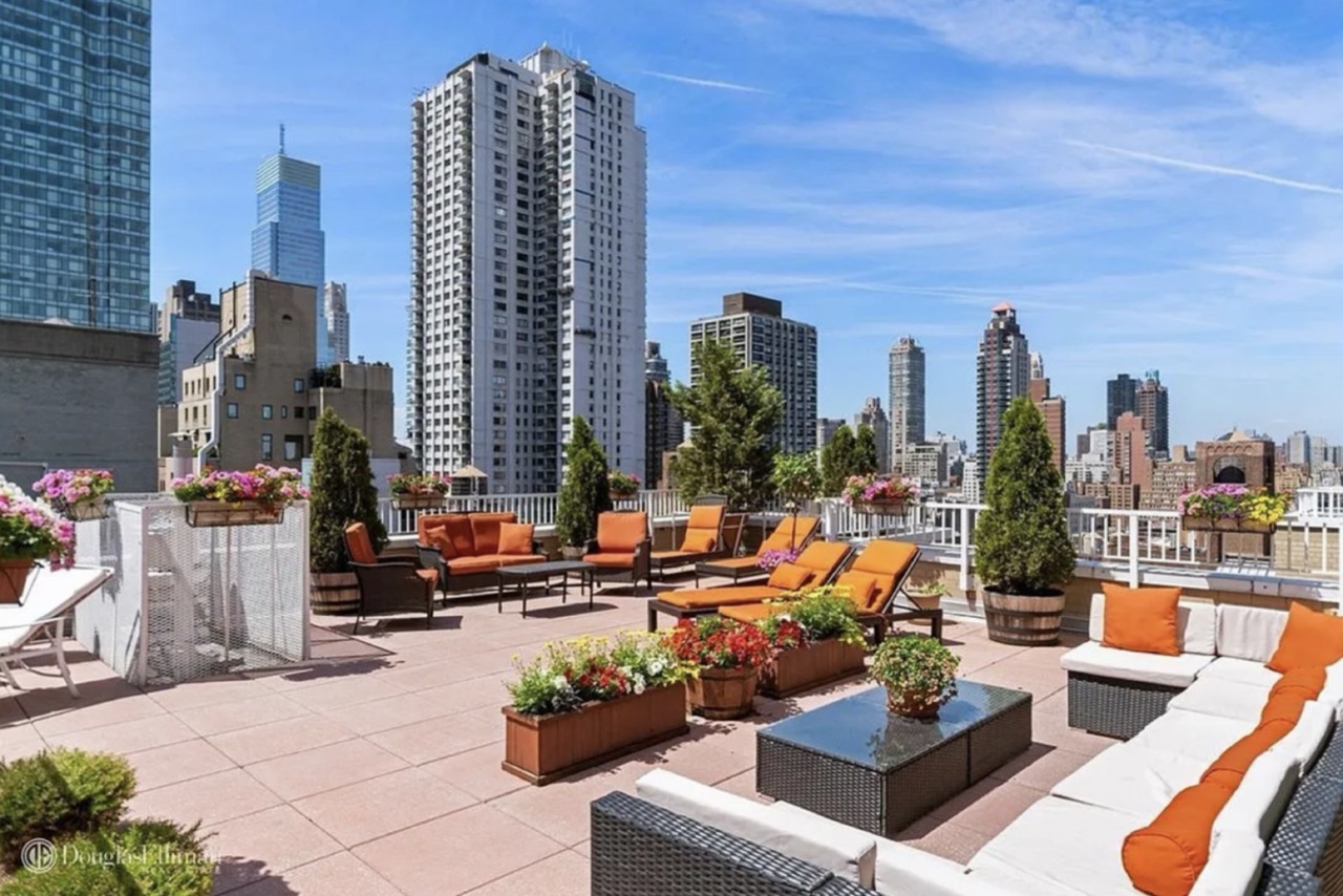 The building's rooftop terrace — substantial outdoor amenity with multiple seating zones, planters, and Sutton Place / Midtown skyline exposure