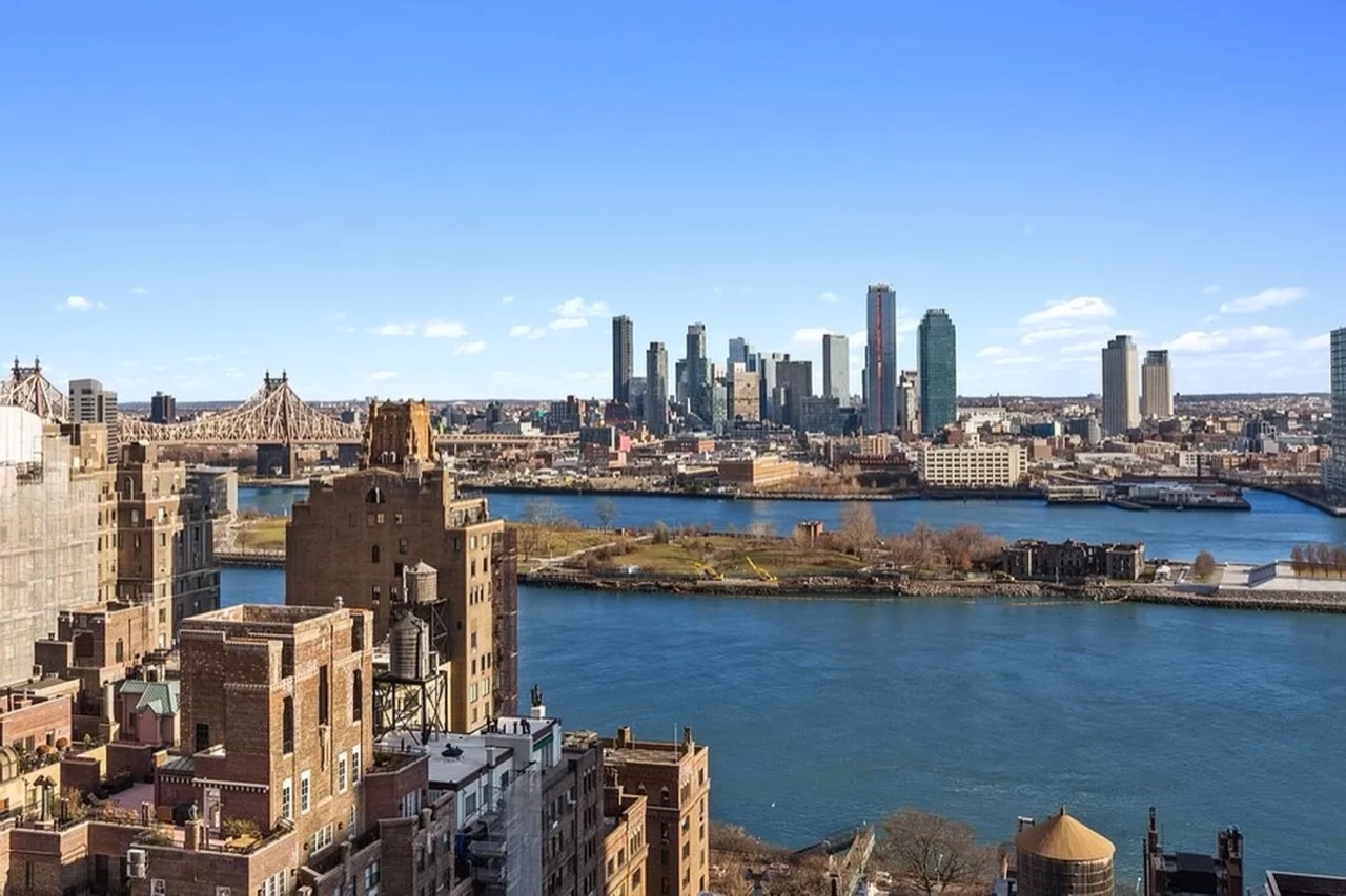 The defining view from #21C — the East River, Queensboro Bridge, Roosevelt Island, and the Long Island City skyline, the waterfront-view criterion the buy-side brief was anchored to