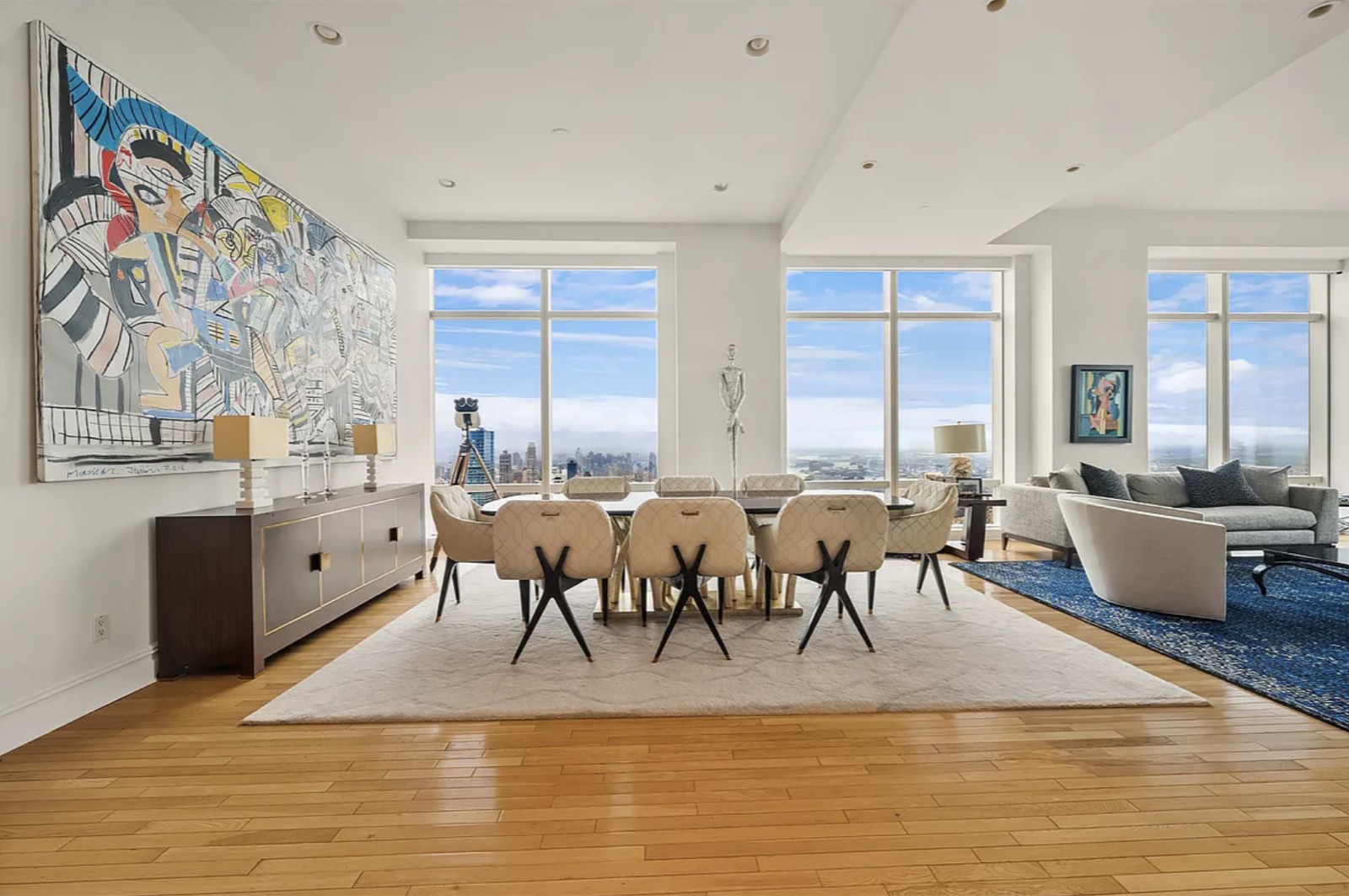 The dining area, with the living room to the right and floor-to-ceiling windows along the far wall