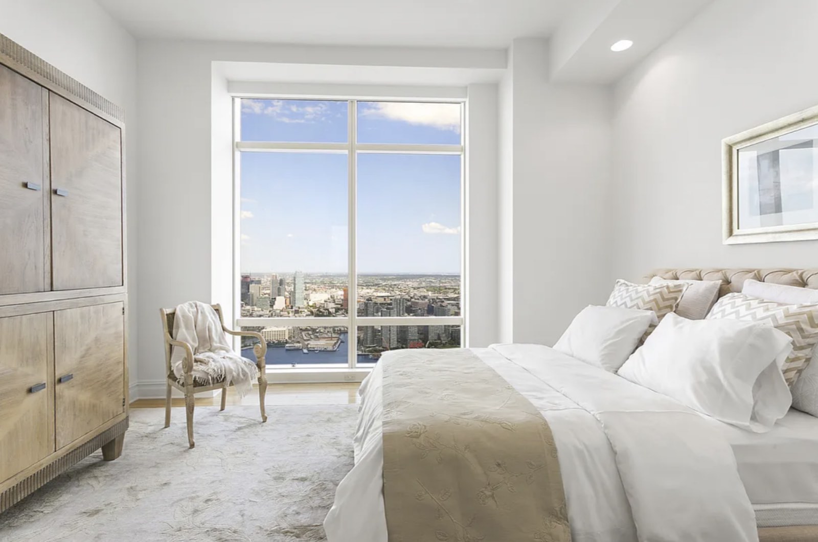 A bedroom at 76A, with a floor-to-ceiling window facing east across the East River toward Long Island City